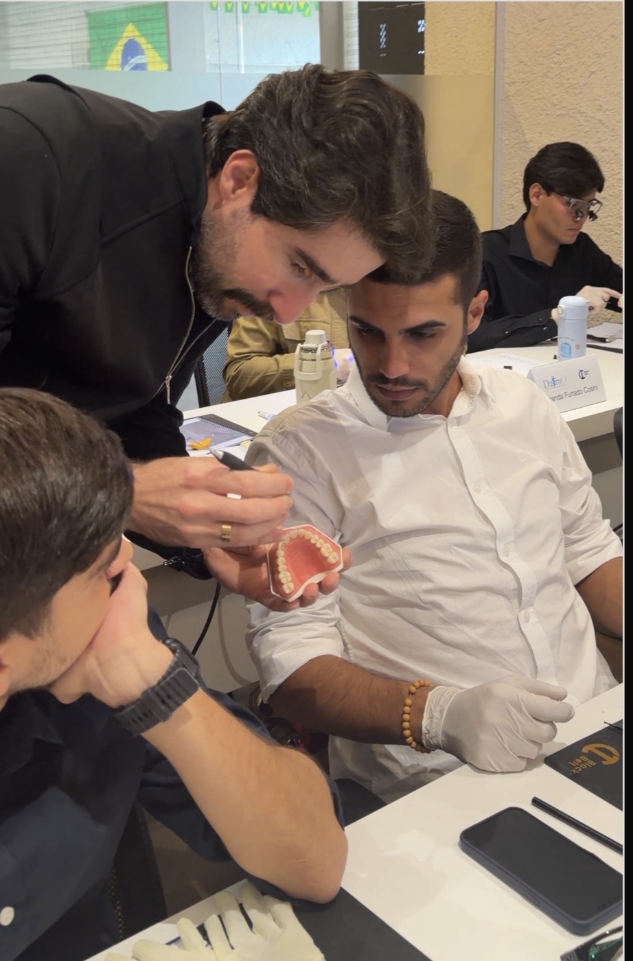 Dr. Gleyber Lemos acompanhando um aluno na bancada durante a prática em manequim